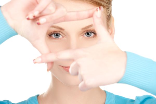 Bela mulher emoldurando os olhos azuis com os dedos. Conceito de cirurgia a laser para doenças oculares.
