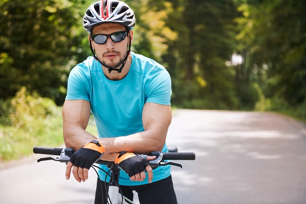 Jovem ciclista usando óculos com proteção solar para atletas.