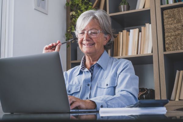 Senhora da 3ª idade trabalhando com um notebook num local bem iluminado. Aparenta saúde ocular perfeita.
O excesso de horas frente a telas é uma das causas da Síndrome do Olho Seco.