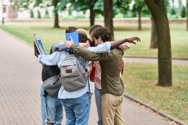 Grupo de jovens estudantes abraçados e felizes com o retorno escolar.