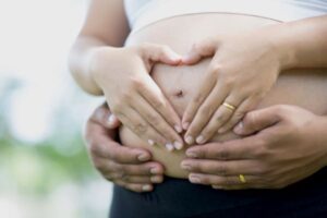 Mãos de um casal sobre a barriga da gestante.