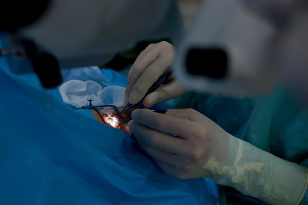Cirurgia ocular sendo realizada por médica que executa manipulações com instrumentos cirúrgicos.