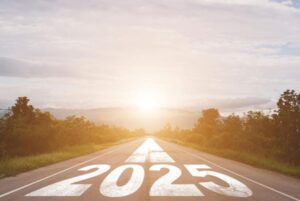 Imagem de uma estrada livre em cuja frente avistam-se o sol e bosques. No centro da estrada está escrito 2025. Conceito de novo ano e novas atitudes.