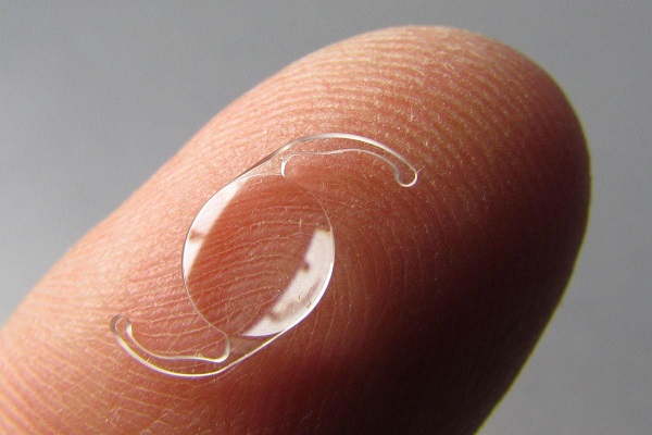 Lente intraocular em cima de um dedo indicador.