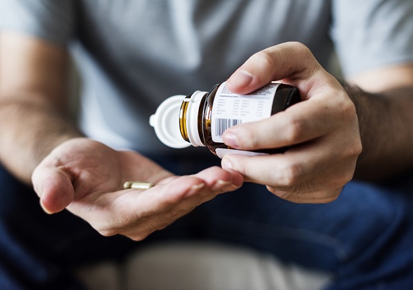 Jovem colocando pílulas de corticoide na mão. Esta medicação pode desencadear catarata em jovens.