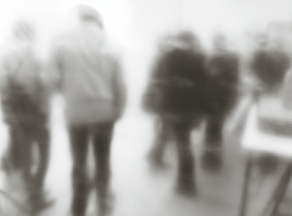 Imagem embaçada, em preto e branco, de várias pessoas caminhando.