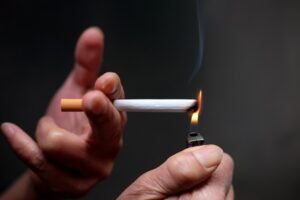 Mãos masculinas acendem um cigarro com isqueiro.
