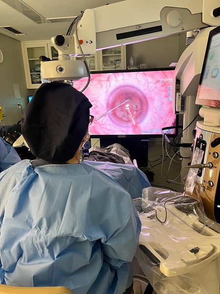 Dra Terla Castro realizando uma cirurgia ocular com a técnica Presbyond. 
Na imagem, ela realiza o procedimento observando o globo ocular ampliado numa tela à sua frente.