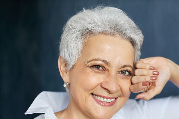 Close no rosto de uma linda mulher idosa, com cabelos curtos e grisalhos, bem maquiada e sorridente.