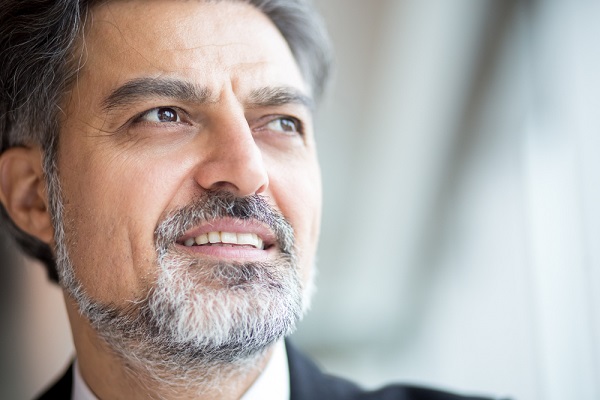 Close do rosto de um elegante empresário com cabelo e barba grisalhos. Sua visão é perfeita após a realização de cirurgia de catarata.