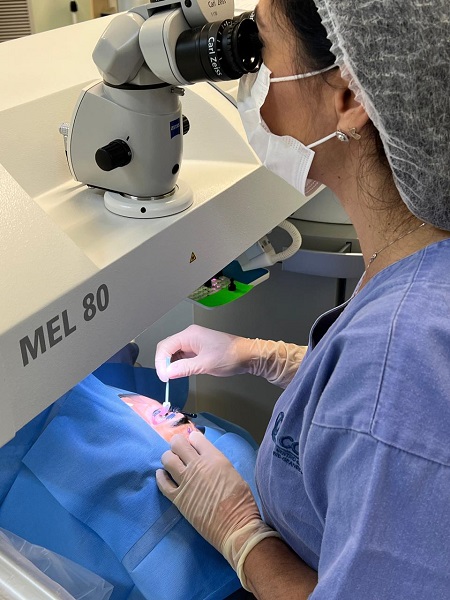 Dra Terla realizando uma cirurgia refrativa. Na imagem, ela manipula o olho do paciente.