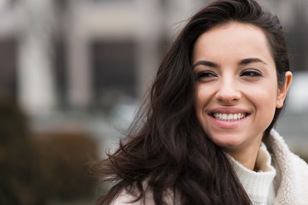 Linda mulher com cabelos longos e escuros, vestindo roupas de inverno sorri feliz. 
As córneas doadas devolvem a visão a milhares de pessoas.